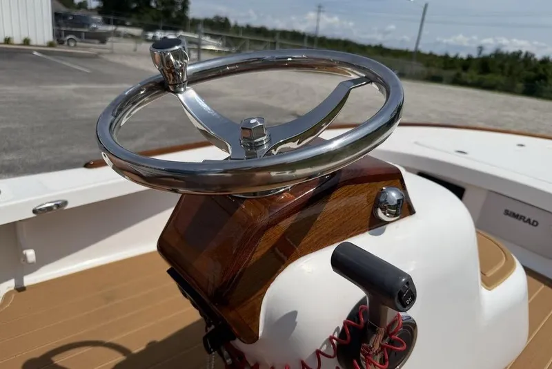Slide: The Image of Steering wheel of a 2012 Chaos 16 Bonefish boat, featuring polished metal and wood accents. - 15