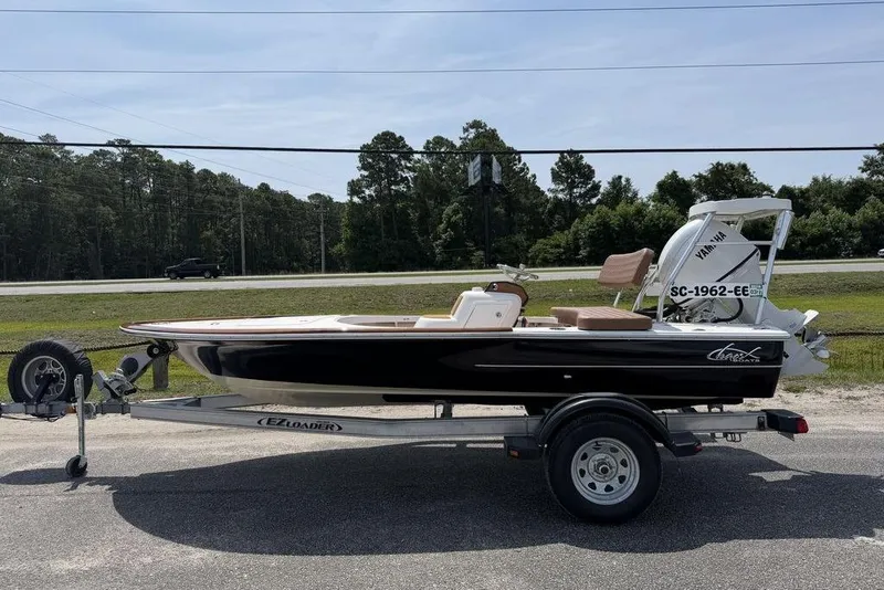 The Image of 2012 Chaos 16 Bonefish boat on trailer, parked roadside with trees in background. - 1