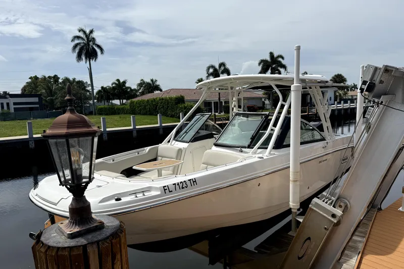 Slide: The Image of 2018 Boston Whaler 230 Vantage boat docked near palm trees and waterfront homes. - 16