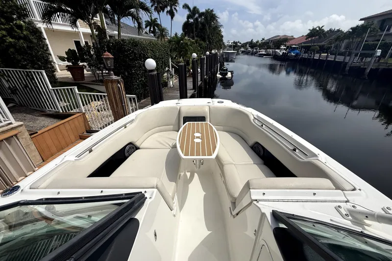 Slide: The Image of 2018 Boston Whaler 230 Vantage boat docked by a serene canal with lush surroundings. - 4