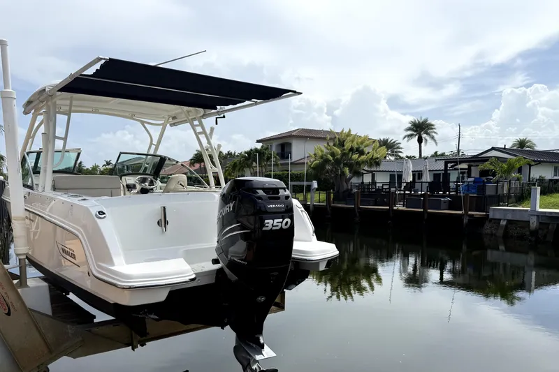 The Image of 2018 Boston Whaler 230 Vantage boat docked by waterfront homes, featuring a Mercury 350 engine. - 0