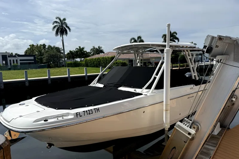 Slide: The Image of 2018 Boston Whaler 230 Vantage boat docked, covered, with palm trees in the background. - 8