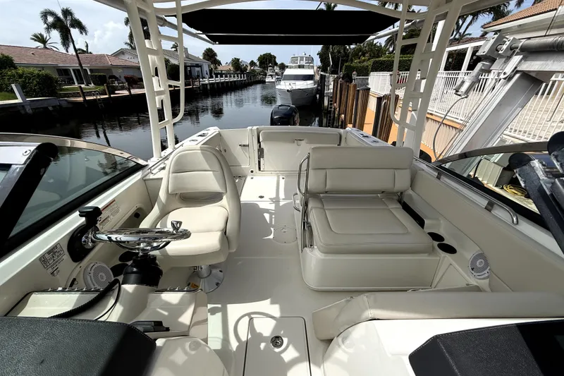 Slide: The Image of 2018 Boston Whaler 230 Vantage boat interior with seating and steering wheel, docked by a canal. - 5