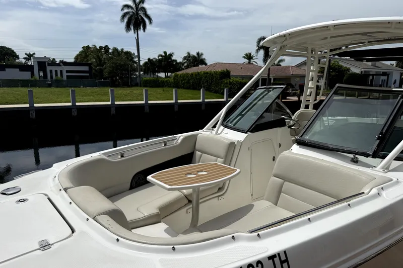 Slide: The Image of 2018 Boston Whaler 230 Vantage boat with seating and table, docked near waterfront homes. - 2