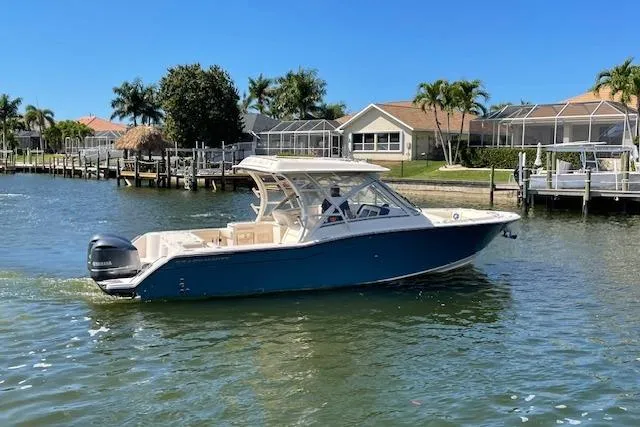 Slide: The Image of 2021 Grady-White Freedom 325 boat cruising on a sunny waterfront near residential docks. - 2