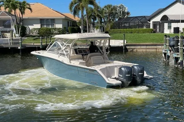 Slide: The Image of 2021 Grady-White Freedom 325 boat with dual engines in a sunny marina setting. - 5