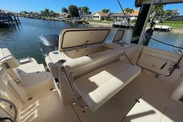 Slide: The Image of 2021 Grady-White Freedom 325 boat interior with seating and storage, docked by a scenic waterfront. - 21