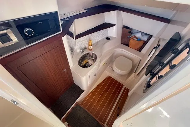Slide: The Image of 2021 Grady-White Freedom 325 boat interior with compact bathroom and wooden accents. - 52