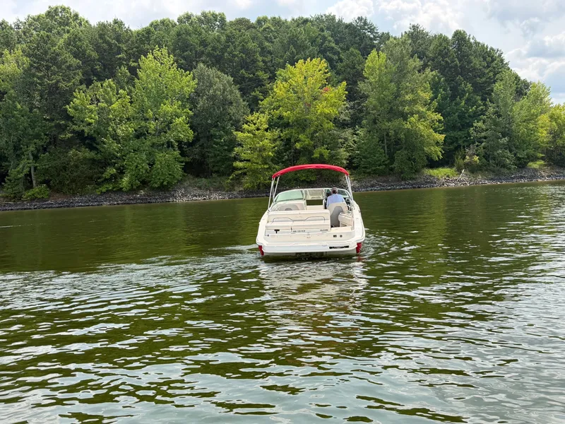 Slide: The Image of A 2009 Sea Ray 230 Sundeck on a calm lake, surrounded by trees. - 2
