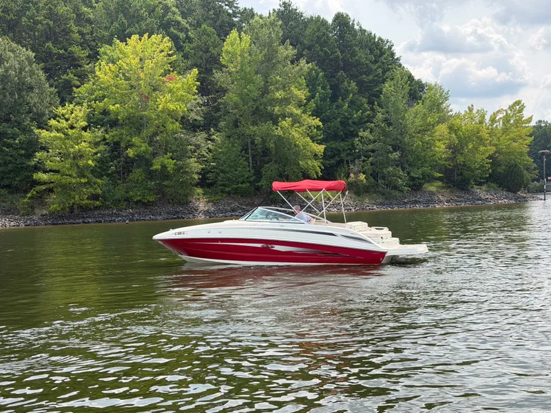 Slide: The Image of A red 2009 Sea Ray 230 Sundeck boat cruising on a calm lake, surrounded by trees. - 4