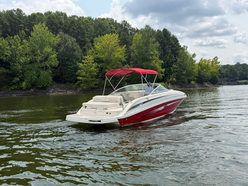 Slide: The Image of A red 2009 Sea Ray 230 Sundeck boat cruising on a calm lake with a wooded shoreline. - 1