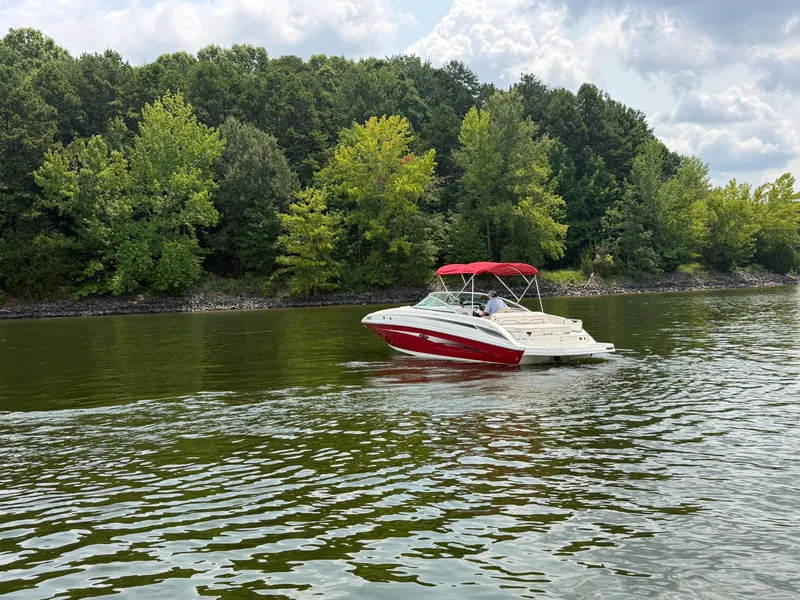 Slide: The Image of A red 2009 Sea Ray 230 Sundeck boat cruising on a calm lake, surrounded by trees. - 3