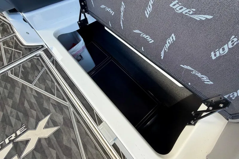 Slide: The Image of 2025 Tigé Ultré 25ZX boat storage compartment with branded interior and geometric flooring design. - 31