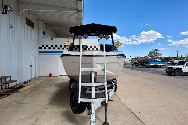 Slide: The Image of 2025 Tigé Ultré 25ZX boat on trailer, parked outside a building under a clear blue sky. - 10