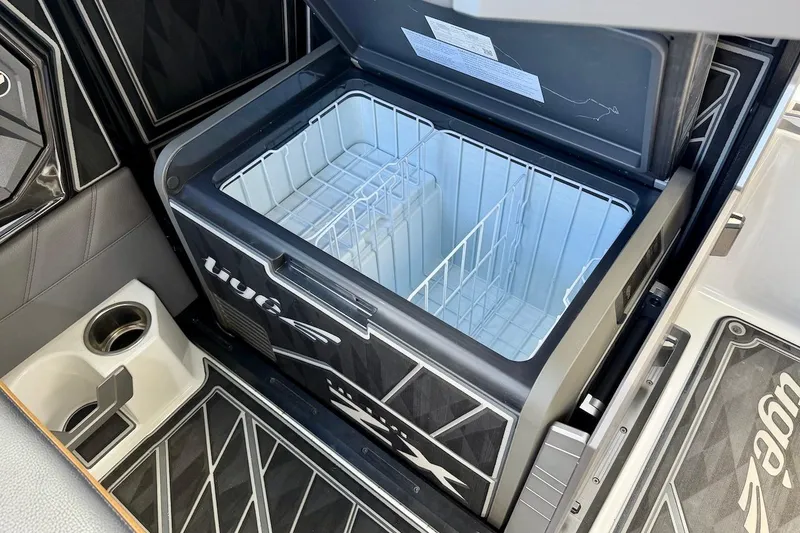 Slide: The Image of Open cooler compartment in 2025 Tigé Ultré 25ZX boat, featuring sleek design and cup holder. - 25