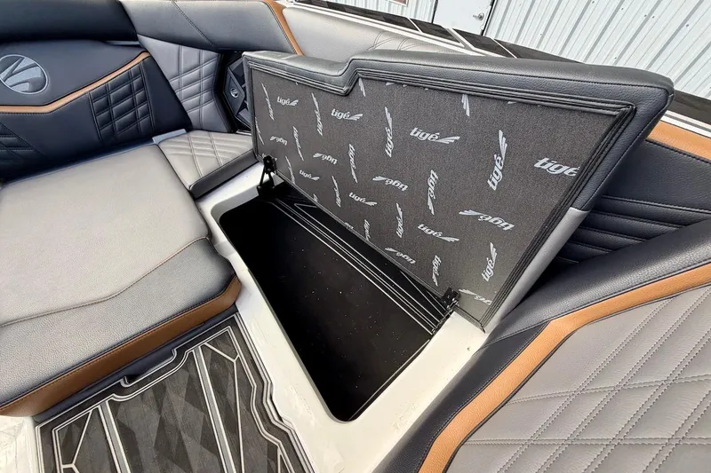 Slide: The Image of 2025 Tigé Ultré 25ZX boat interior with open storage compartment and stylish seating. - 24