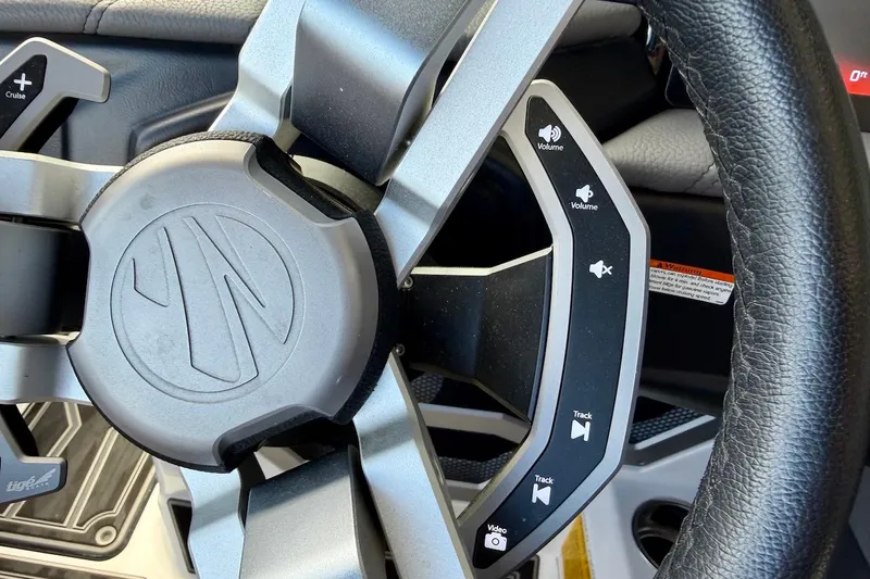Slide: The Image of Steering wheel controls of 2025 Tigé Ultré 25ZX boat, featuring volume and track buttons. - 38