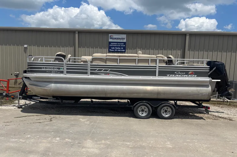 The Image of 2020 Sun Tracker Fishin' Barge 22 XP3 pontoon boat on trailer, parked outdoors. - 0
