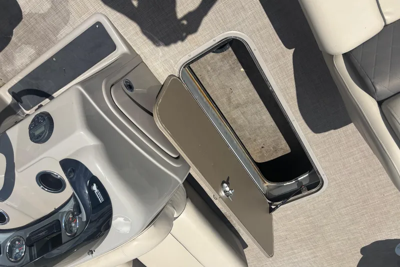 Slide: The Image of 2020 Sun Tracker Fishin' Barge 22 XP3 interior with open storage compartment and control panel. - 13
