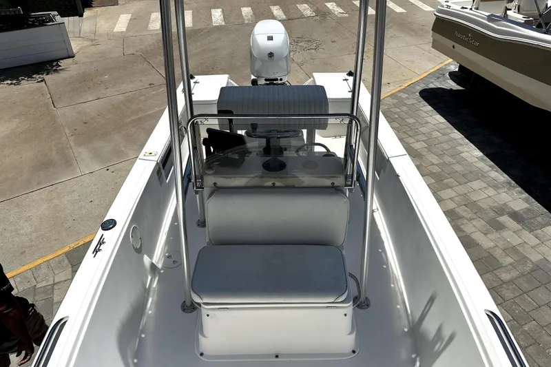 Slide: The Image of 2004 Aquasport 175 Osprey boat interior with seating and console, parked on pavement. - 8