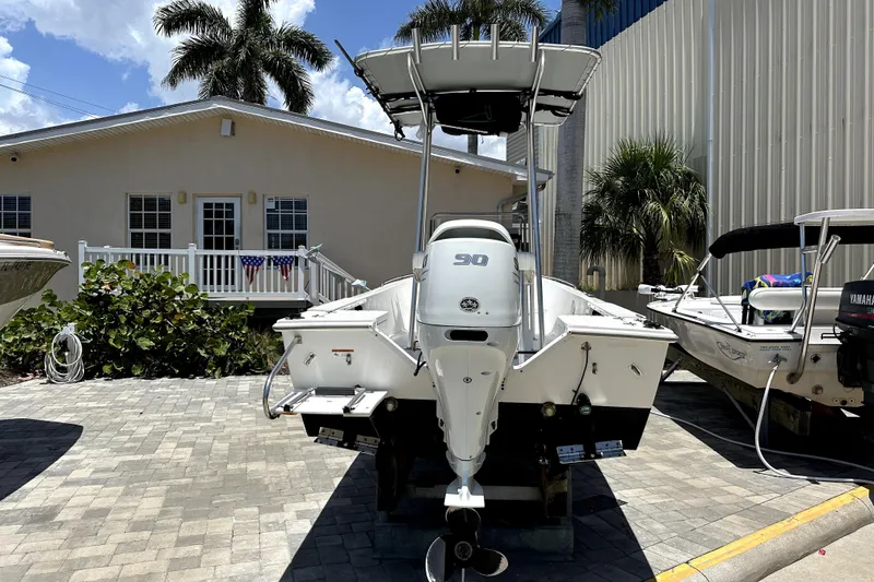 Slide: The Image of 2004 Aquasport 175 Osprey boat with outboard motor, parked near a house and palm trees. - 5