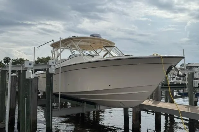 Slide: The Image of 2024 Grady-White Freedom 335 boat docked on a lift under cloudy skies. - 2