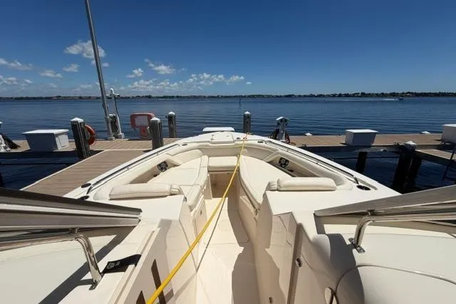 Slide: The Image of 2024 Grady-White Freedom 335 boat docked, showcasing spacious seating and serene waterfront view. - 6