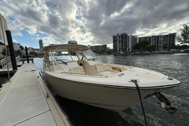 Slide: The Image of 2024 Grady-White Freedom 335 boat docked by waterfront under cloudy sky. - 1
