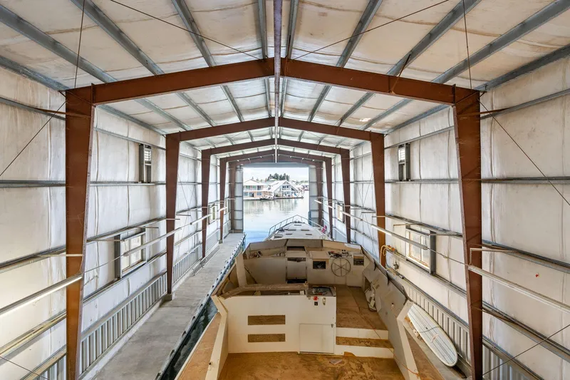 Slide: The Image of Interior view of a 1985 Custom Larson Boathouse with a boat docked inside. - 11