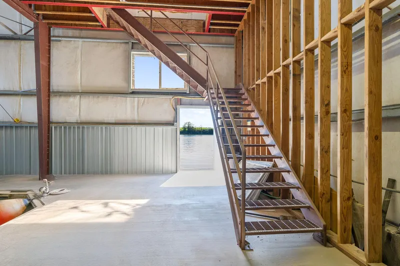 Slide: The Image of Industrial interior of 1985 Custom Larson Boathouse with metal staircase and wooden beams. - 7