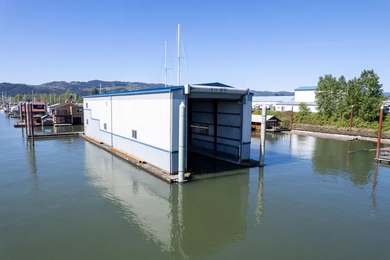 Slide: The Image of Custom 1985 Larson Boathouse floating on calm water under clear blue sky. - 28