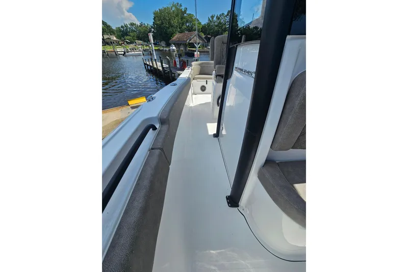 Slide: The Image of 2027 Sea Hunt Ultra 245 SE boat docked by a scenic waterfront. - 25