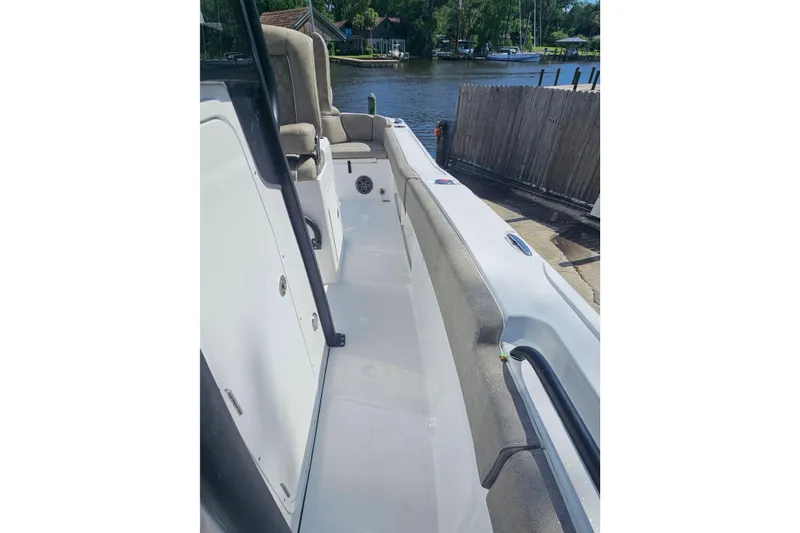 Slide: The Image of 2027 Sea Hunt Ultra 245 SE boat interior with seating, docked by a serene waterfront. - 24