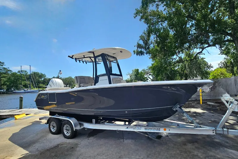 Slide: The Image of 2027 Sea Hunt Ultra 245 SE boat on trailer, dockside with trees in background. - 4