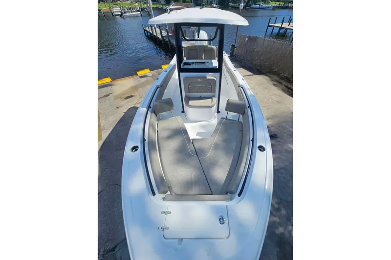 Slide: The Image of 2027 Sea Hunt Ultra 245 SE boat docked, showcasing spacious deck and seating area. - 28