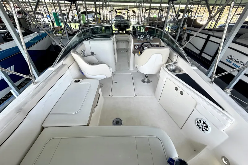 Slide: The Image of 2013 Sea Ray 260 Sundeck interior with seating, steering wheel, and sink in a marina. - 13