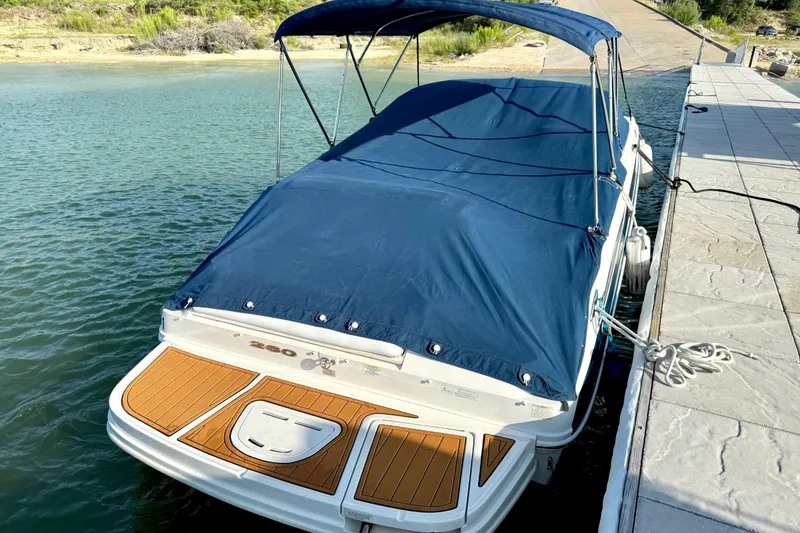 Slide: The Image of 2013 Sea Ray 260 Sundeck boat docked with blue cover and wooden deck. - 29