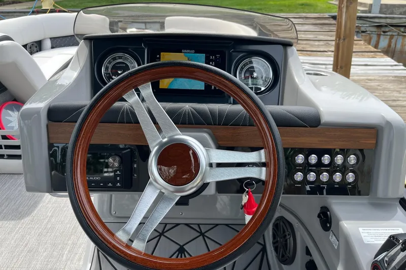 Slide: The Image of 2024 Harris Grand Mariner 250 dashboard with wood-accented steering wheel and modern controls. - 6