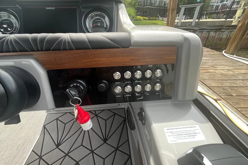 Slide: The Image of 2024 Harris Grand Mariner 250 dashboard with controls and ignition key. - 11