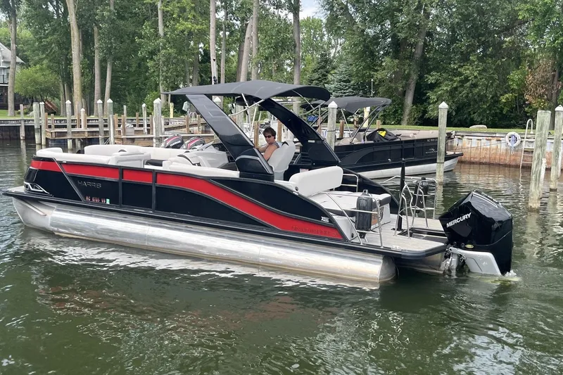 Slide: The Image of 2024 Harris Grand Mariner 250 pontoon boat docked on a calm lake. - 5