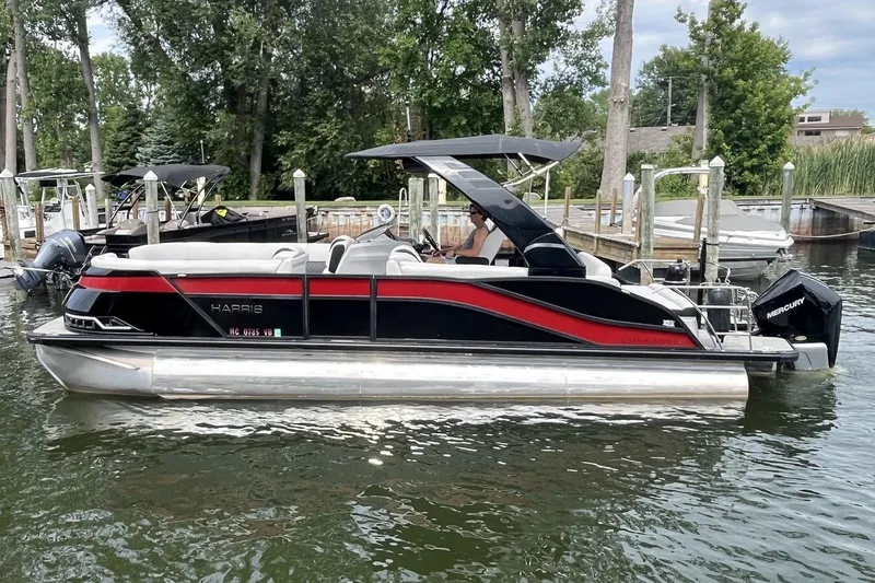Slide: The Image of 2024 Harris Grand Mariner 250 pontoon boat docked on a calm lake. - 4