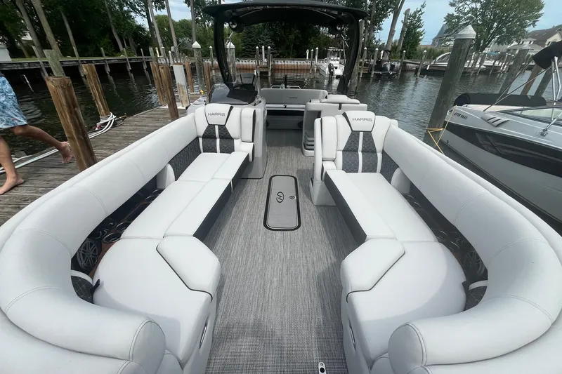 Slide: The Image of 2024 Harris Grand Mariner 250 pontoon boat with luxurious seating at a dock. - 12