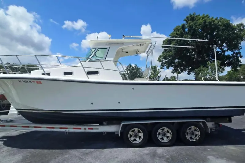 Slide: The Image of 2003 True World Marine 286 boat on trailer under blue sky. - 2