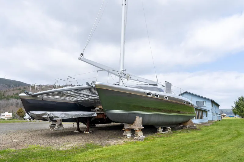 Slide: The Image of Shuttleworth 52 AeroRig catamaran, 2025 model, on land with a scenic backdrop. - 5