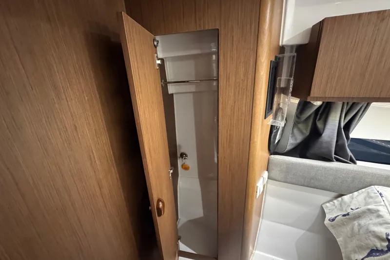 Slide: The Image of 2024 Beneteau Antares 9 interior with wooden cabinetry and compact storage space. - 21