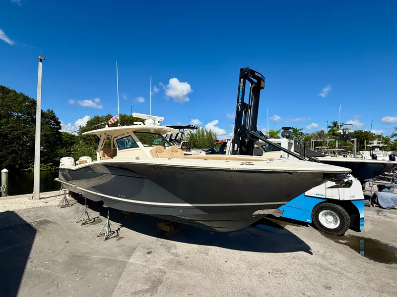 The Image of A 2021 Scout 380 boat is on a dry dock under a blue sky. - 0