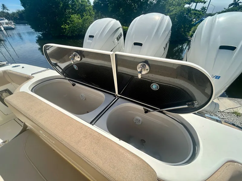 Slide: The Image of The image shows the rear of a Scout 380 boat with open storage compartments and three outboard engines. - 8