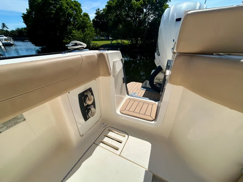 Slide: The Image of A 2021 Scout 380 boat with beige upholstery and wooden flooring, docked by the water. - 26