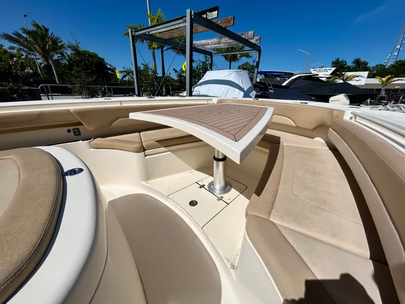 Slide: The Image of The image shows the bow area of a 2021 Scout 380 boat with a table and seating. - 13