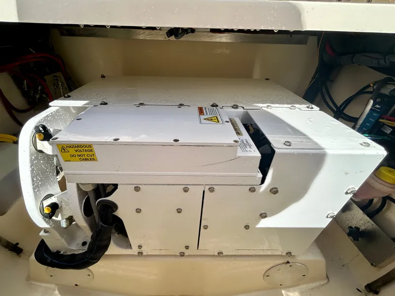 Slide: The Image of An engine compartment with a white generator, surrounded by cables and hoses. - 25